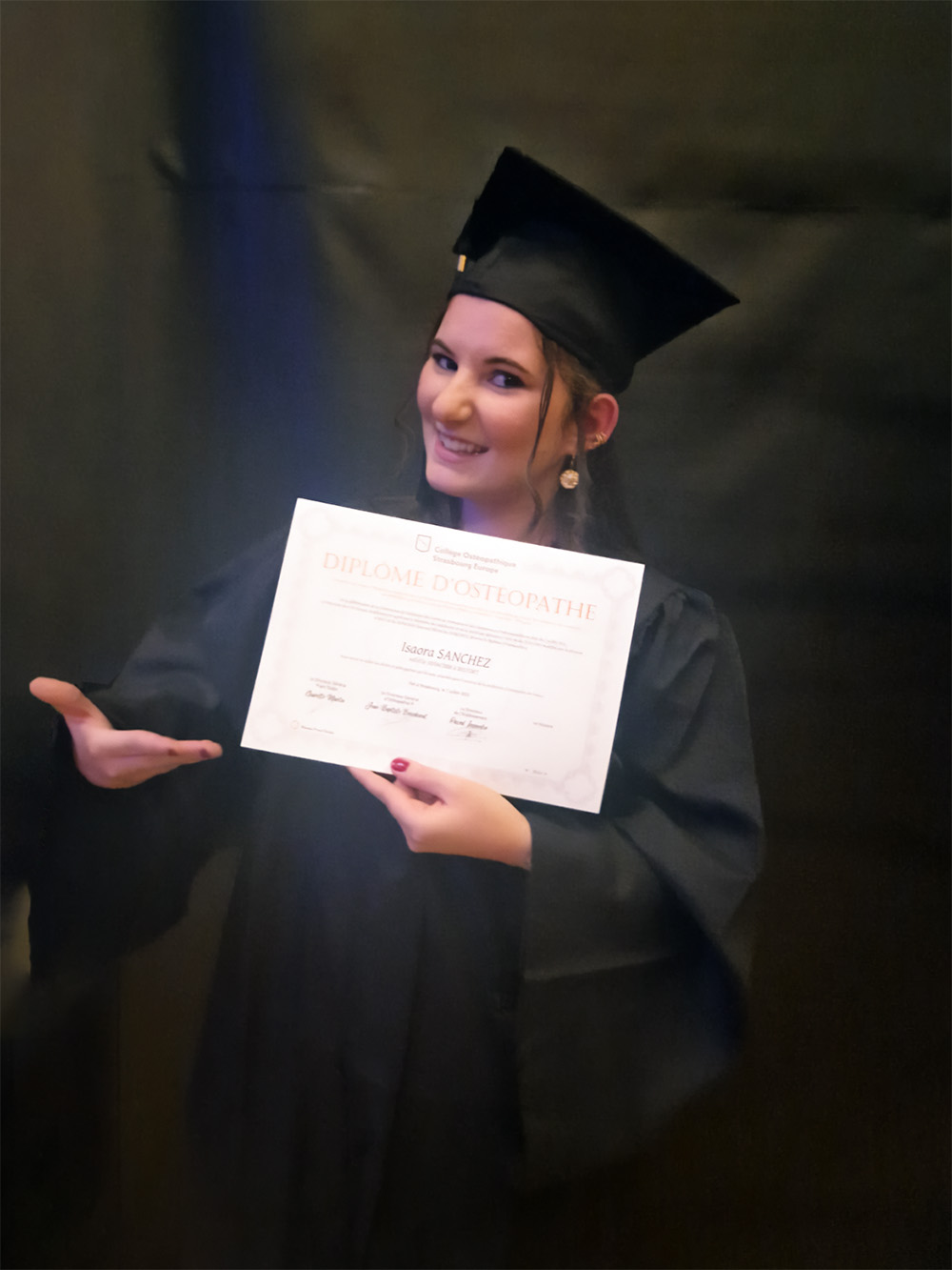 Photo d'Isaora Ostéopathe DO avec son diplôme sur fond noir